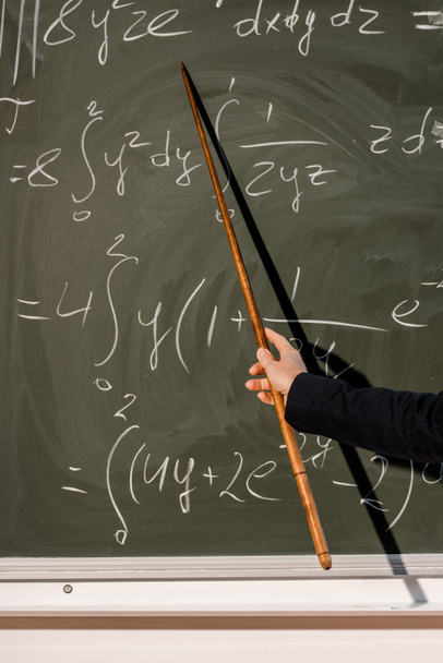 vista recortada de maestra con puntero de madera explicando ecuaciones matemáticas en el aula
 - Foto, Imagen