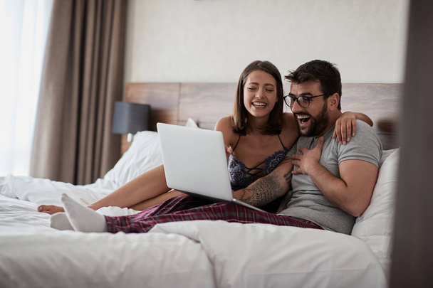 People, sexual, technology concept- happy couple watching video on laptop laughing together - 写真・画像