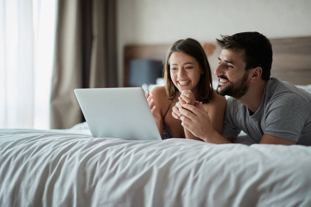 Man and woman at home surfing the net in bed at morning - Foto, imagen