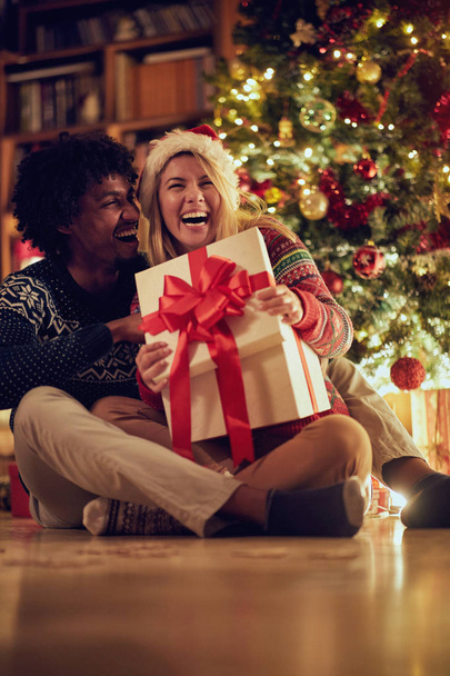 Happy male and female exchanging Christmas presents and having fun - Fotografie, Obrázek