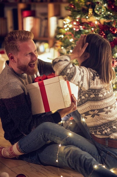 romantic surprise holiday  Cheerful young man and woman with gift enjoying together on Christmas eve - 写真・画像