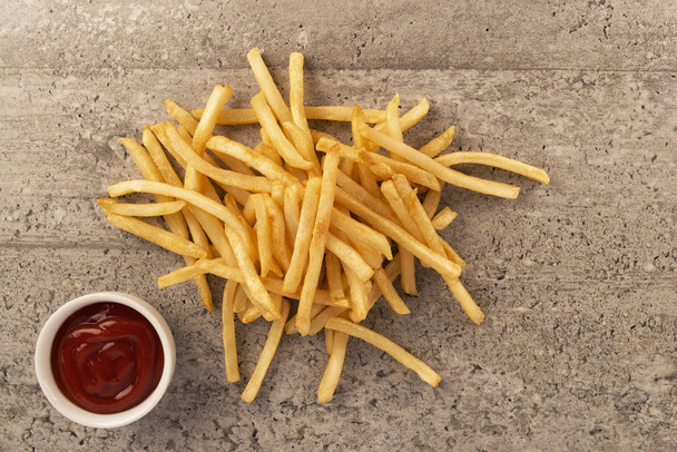 French fries with ketchup on concrete background, directly above. Close up. - Photo, Image