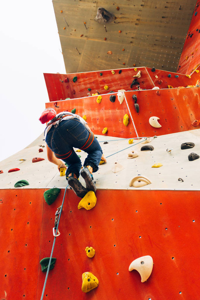 Nuori mies harjoittelee kiipeilyä ulkona kiipeilytelineessä
 - Valokuva, kuva