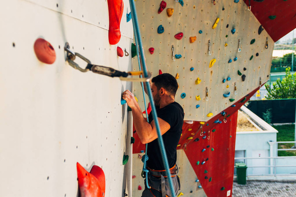Jeune grimpeur grimpant sur un rocher pratique au centre d'escalade, bloc - Photo, image