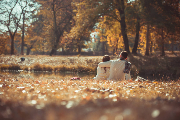 Uroczy para zakochanych siedzi od trawa w parku i przytulanie - Zdjęcie, obraz