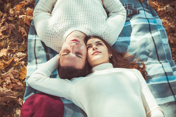 Herrliches Paar verbringt Herbsttag im Park, auf einer Decke liegend und umarmt - Foto, Bild