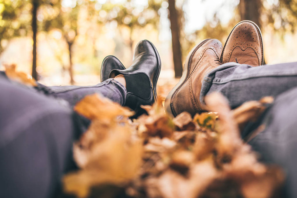Cute couple is resting in the park and showing their boots - Foto, afbeelding