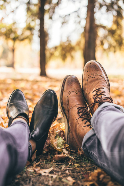 A stylish couple is lying in the park showing their boots - Photo, Image