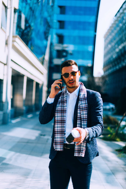 Νεαρός επιχειρηματίας, μιλώντας στο κινητό τηλέφωνο στο οικονομικό κέντρο της πόλης. - Φωτογραφία, εικόνα