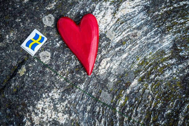Дерев'яні червоне серце і Шведська прапор на фоні моховий рок. Скандинавської природи. - Фото, зображення