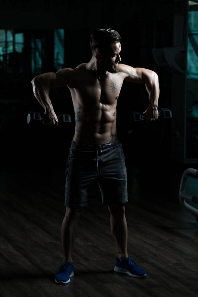 спортсмен Робота плечі з гантелями в спортзалі
 - Фото, зображення