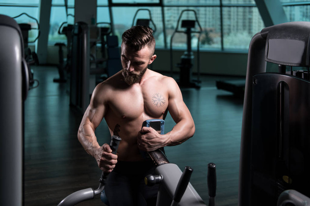 Handsome Bodybuilder Doing Heavy Weight Exercise For Back On Machine - Foto, imagen
