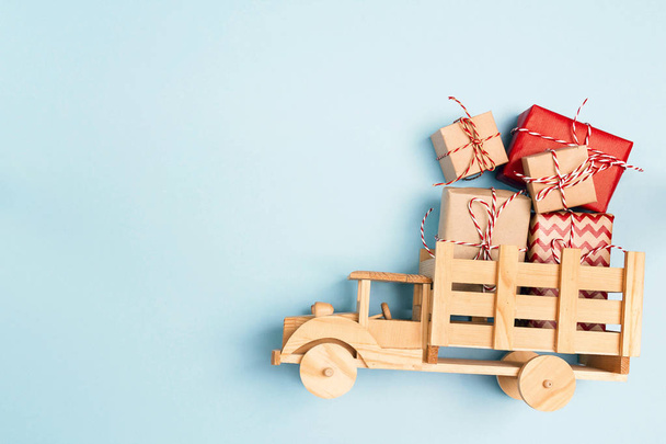 Wooden toy truck  with Christmas gift boxes on blue background and copy space. Top view. - Fotoğraf, Görsel