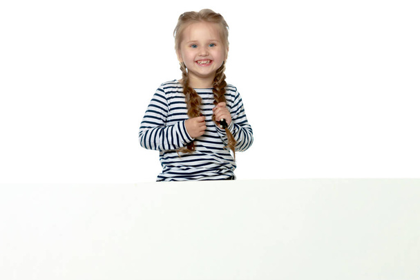 A little girl is looking from behind an empty banner. - Fotó, kép