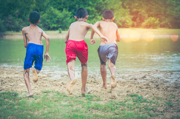 Азиатский мальчик бегает с забавным соревнованием. У каждого есть цель прямо на берегу озера. Пейзаж лета, наполненный зеленым лесом и большим пресноводным бассейном
. - Фото, изображение