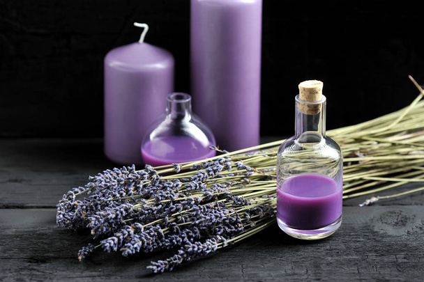 lavendel, lavendelolie en Lila kaarsen op donkere houten achtergrond - Foto, afbeelding