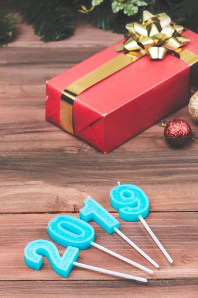 New year festive blue candles year 2019 shape, soft focus of one red gift box, vertical lay out. Coming of better future new year concept. - Photo, Image