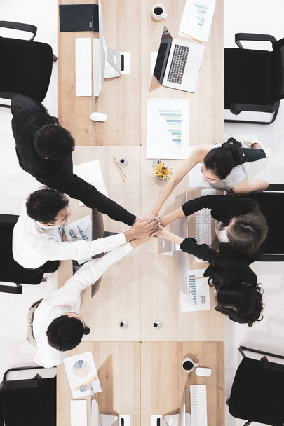 Equipe profissional de análise de negócios colocar as mãos juntas como símbolo de trabalho em equipe e olhando para cima, fundo de computadores mesa de trabalho, vista superior
. - Foto, Imagem