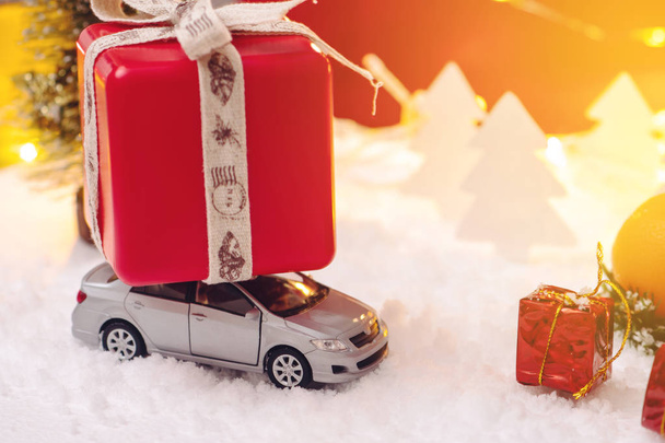 Spielzeugauto trägt Geschenke in der Weihnachts- und Neujahrsnacht auf blauem Grund. das Konzept der Weihnachtseinkäufe und Rabatte - Foto, Bild