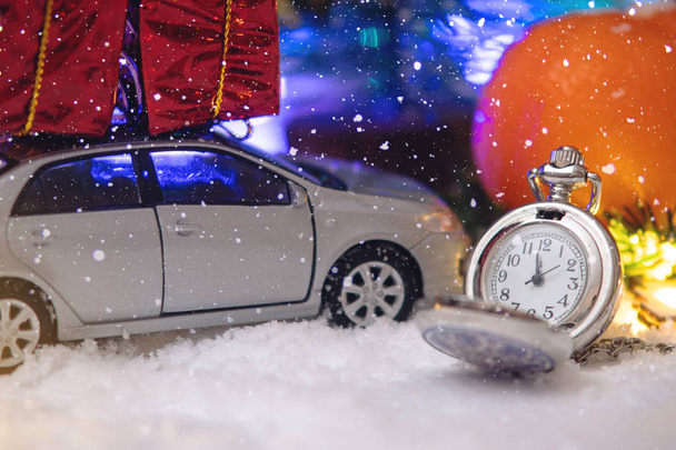 Карманные часы в снегу с автомобилем и подарками накануне праздников. Концепция в ожидании волшебства Рождества и Нового года
 - Фото, изображение