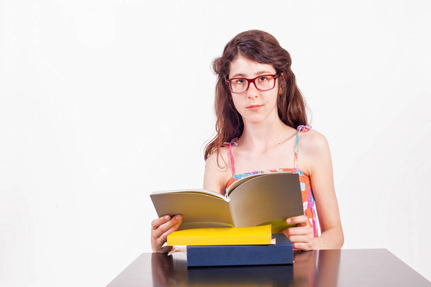 Dospívající dívka sedí u stolu s kniha, studium, studio izolované na bílém - Fotografie, Obrázek
