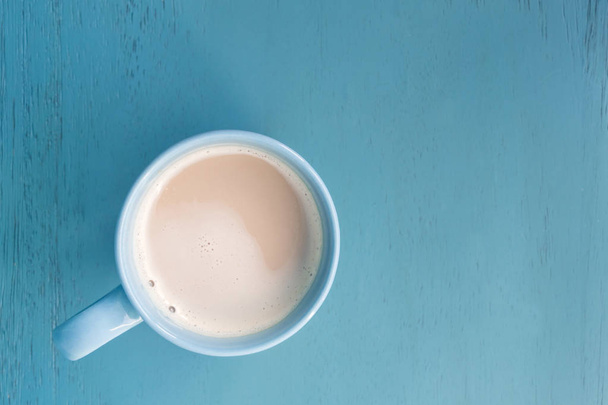 Milk coffee in a blue cup on pastel blue wooden floor - Foto, Imagen