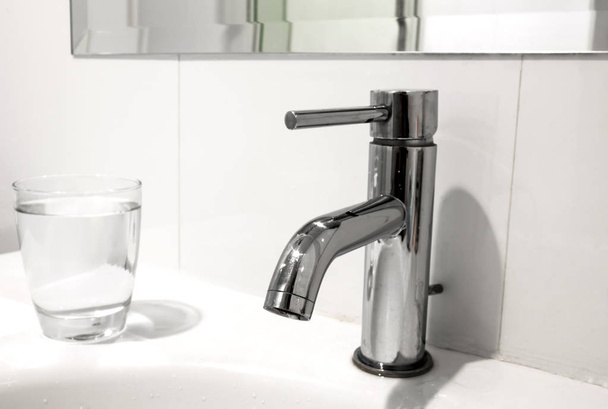 White bathroom faucet and wash basin with water glass - Zdjęcie, obraz
