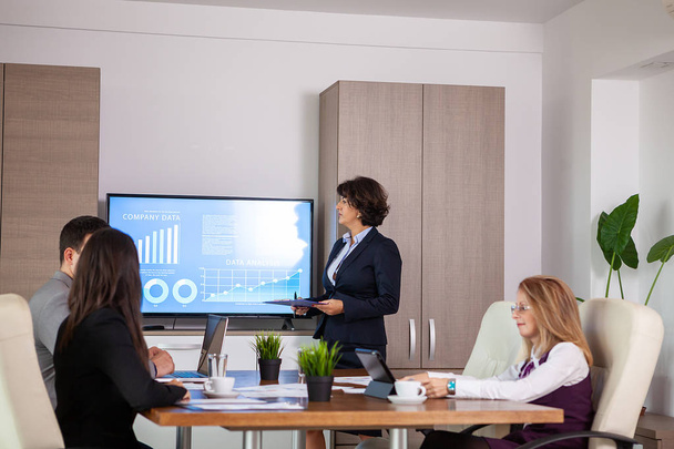 Empreendedores e empresários de sucesso na sala de conferências analisando gráficos e diagramas em uma TV
 - Foto, Imagem