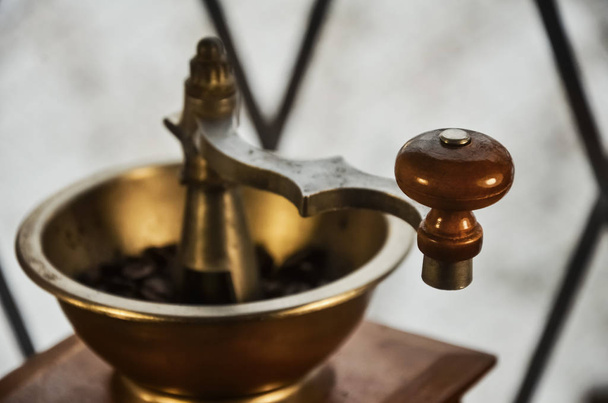Old antique coffee grinder with coffee beans on a wooden windowsill. Blurred image of the winter landscape outside the window. - Fotoğraf, Görsel