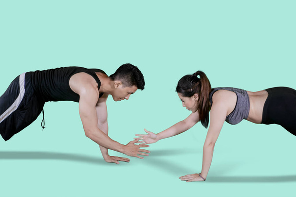 Picture of Asian couple clapping hands while doing push ups together in the studio - Фото, зображення