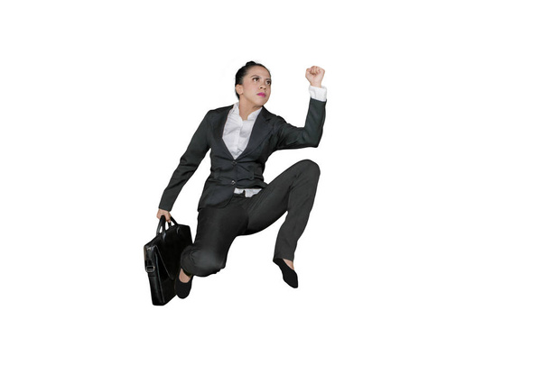Low angle view of female manager carrying a suitcase while sprinting on the studio, isolated on white background - Foto, Imagen