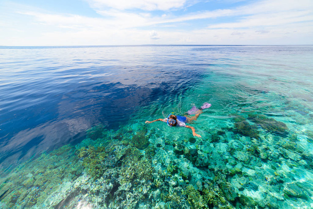 Nő búvárkodás korallzátony trópusi karibi tenger, türkiz kék víz. Indonézia Wakatobi szigetcsoport, tengeri nemzeti park, turisztikai búvárkodás úticél - Fotó, kép