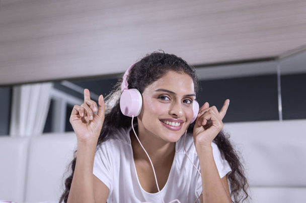 Picture of a young woman enjoying music by using a headset while lying on the bed - Valokuva, kuva