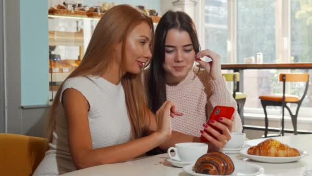 Vonzó vidám nők nevetve a kamera segítségével okos telefon együtt - Felvétel, videó