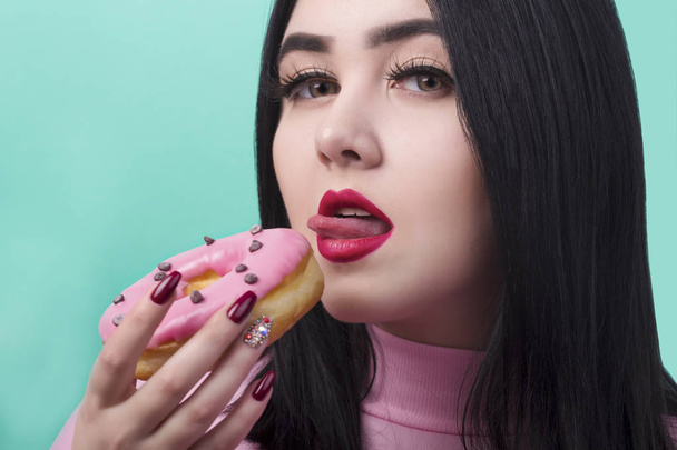 woman with red lips with donuts in her hand prepare to eat it and lick it, on azure background - Photo, Image