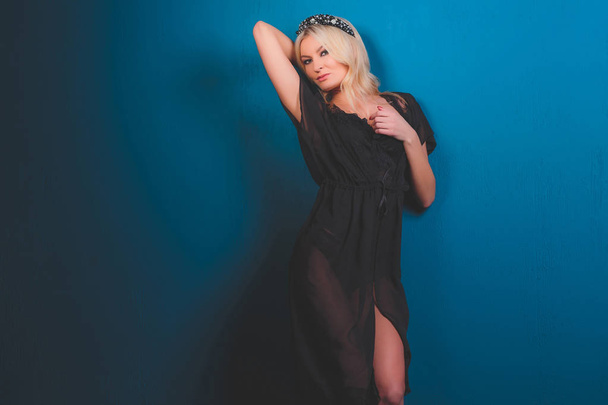 girl blonde on a blue background in a black baud and hat. - Foto, Imagem
