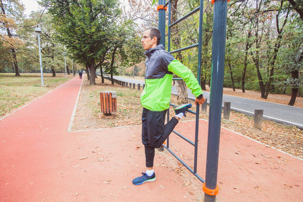 Fitness nuori mies tekee venyttely liikunta ulkona urheilupuisto aamulla. Terveellinen elämäntapa workout
. - Valokuva, kuva