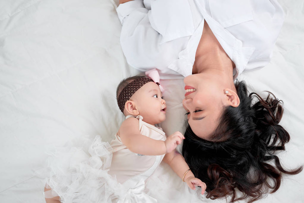 Cute little baby girl and mother lying on bed - Foto, Imagem