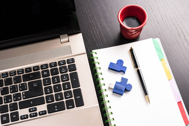 Stilleven met blocknote, laptop, pen en een rode kop koffie over een zwart Bureau. symbool van de baan - Foto, afbeelding