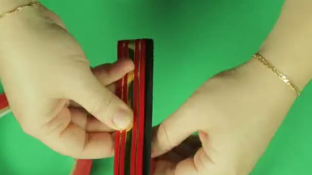 Making a gift bow in red on a green background. Time laps. - Πλάνα, βίντεο