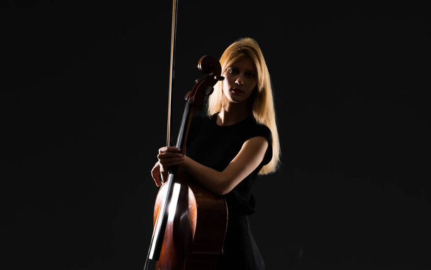Giovane ragazza che suona il violoncello su sfondo nero isolato
 - Foto, immagini
