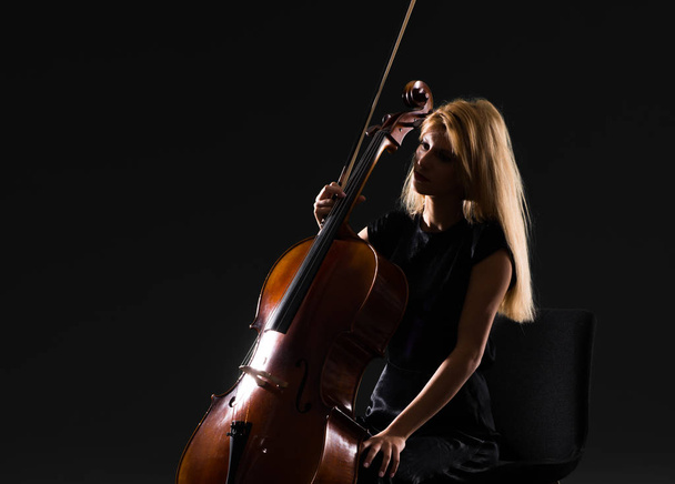 Young girl playing the cello on isolated black background - Фото, зображення