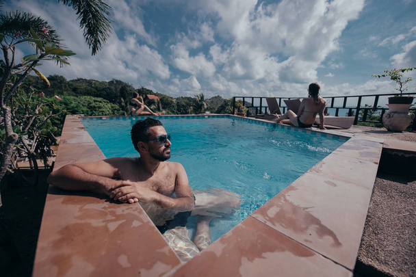 Retrato de un joven guapo en una piscina al aire libre. Tipo atractivo con barba al lado de la piscina
 - Foto, imagen