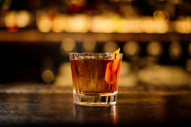 Elegant glass filled with strong cocktail with whiskey on the bar against the lights - 写真・画像