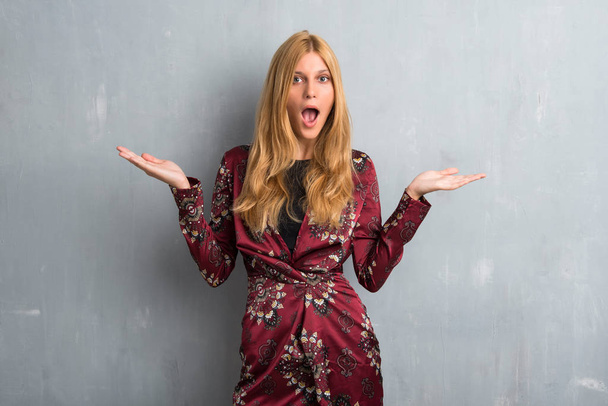 Blonde woman with surprise and shocked facial expression. Mouth open because not expect what has happened on textured wall background - Photo, Image