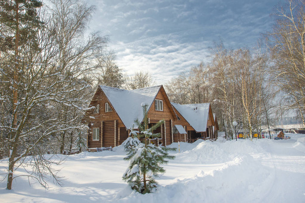 Snow-covered landscape with trees and blue sky, Russian winter. Wooden house. - Foto, afbeelding