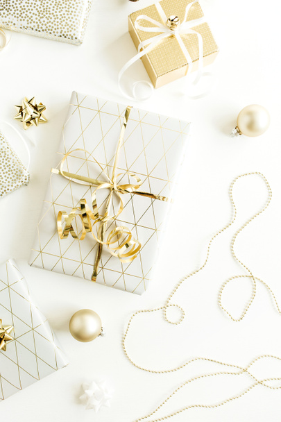 Kerstmis, Nieuwjaar vakantie samenstelling met gouden geschenkdozen, decoraties op witte achtergrond. Plat lag, bovenaan weergave van geschenken, verpakking. - Foto, afbeelding
