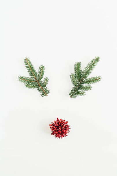 Navidad, Año Nuevo concepto mínimo. Símbolo de ciervo navideño hecho de ramas de abeto y pompón rojo aislado sobre fondo blanco. Piso tendido, vista superior
. - Foto, imagen