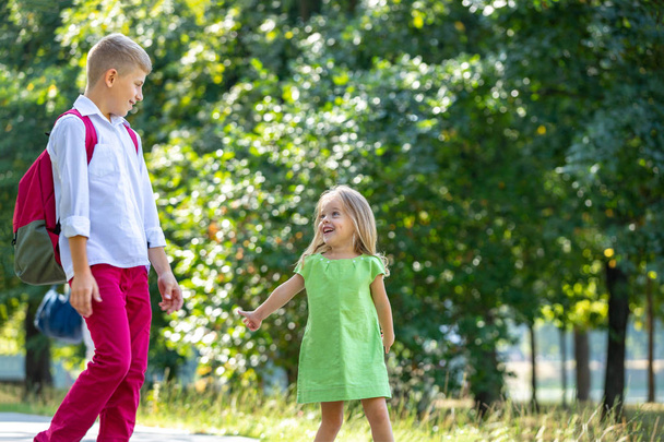 fröhlich lachende Kinder, die im Park spielen und Spaß haben. Porträt im Freien an einem sonnigen Sommertag. Älterer Bruder spaziert mit jüngerer Schwester im Park - Foto, Bild
