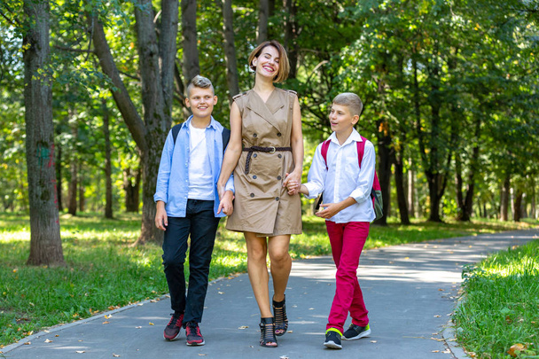 Joyeux jeune famille, mère avec deux garçons marchant dans le parc. Concept de mode de vie sain
 - Photo, image